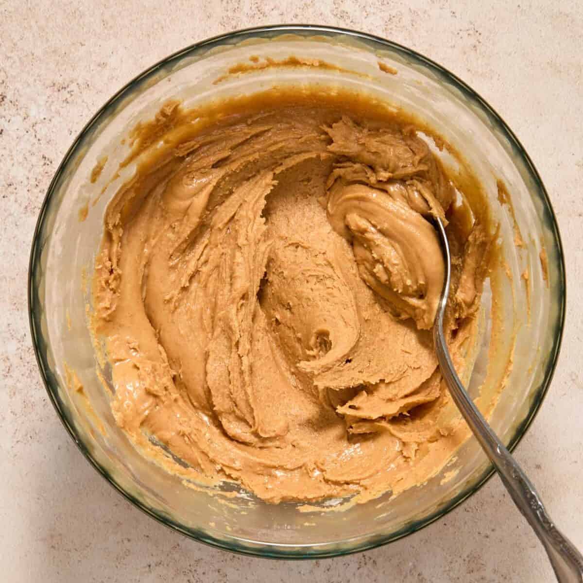 Peanut butter, powdered sugar and other ingredients mixed in bowl with spoon.