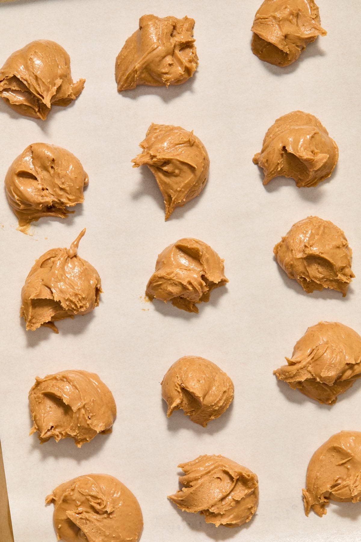 Peanut butter dollops on parchment lined pan.