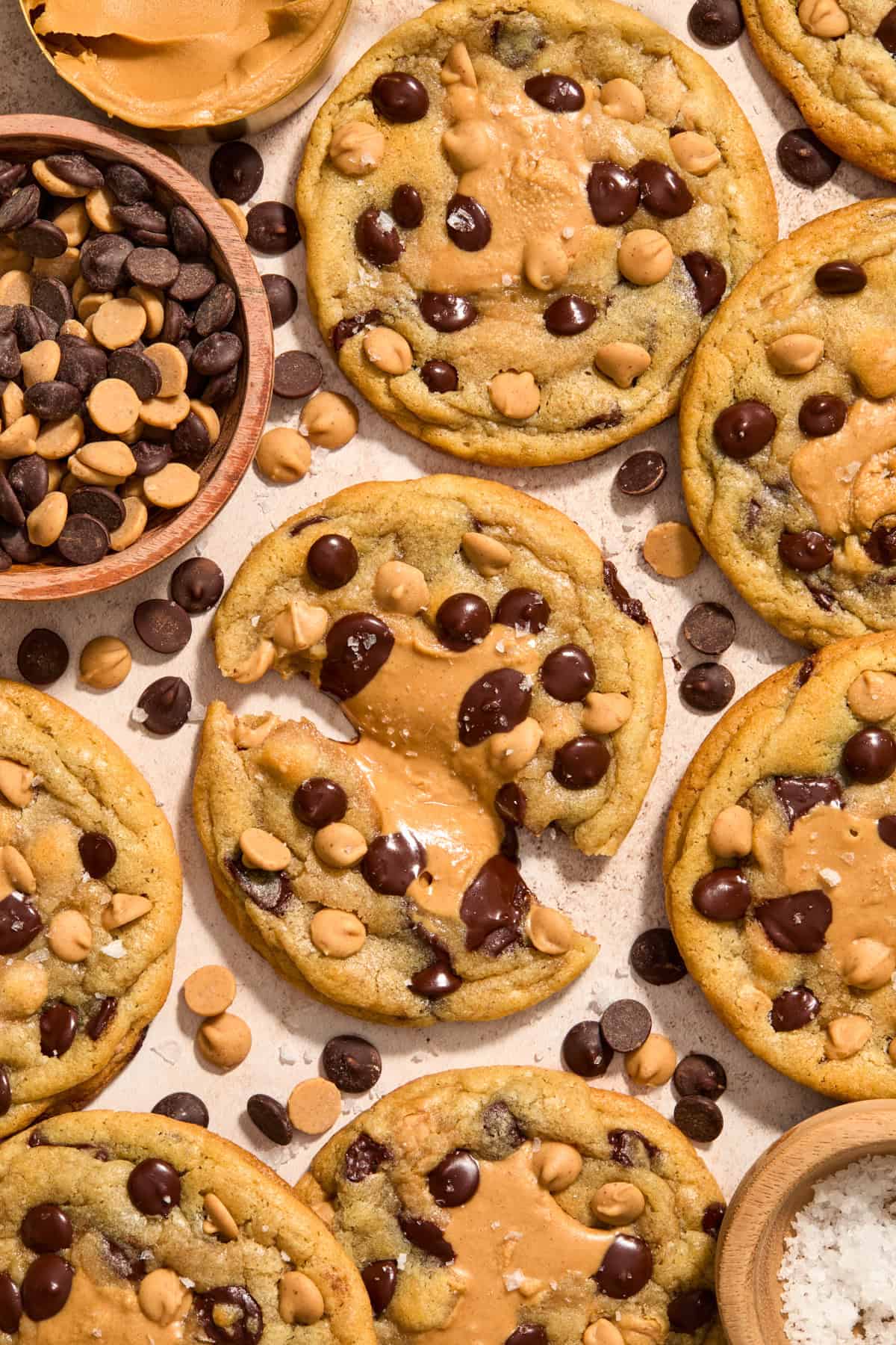 Peanut butter stuffed chocolate chip cookies on surface with one cookie pulled apart to show peanut butter center.