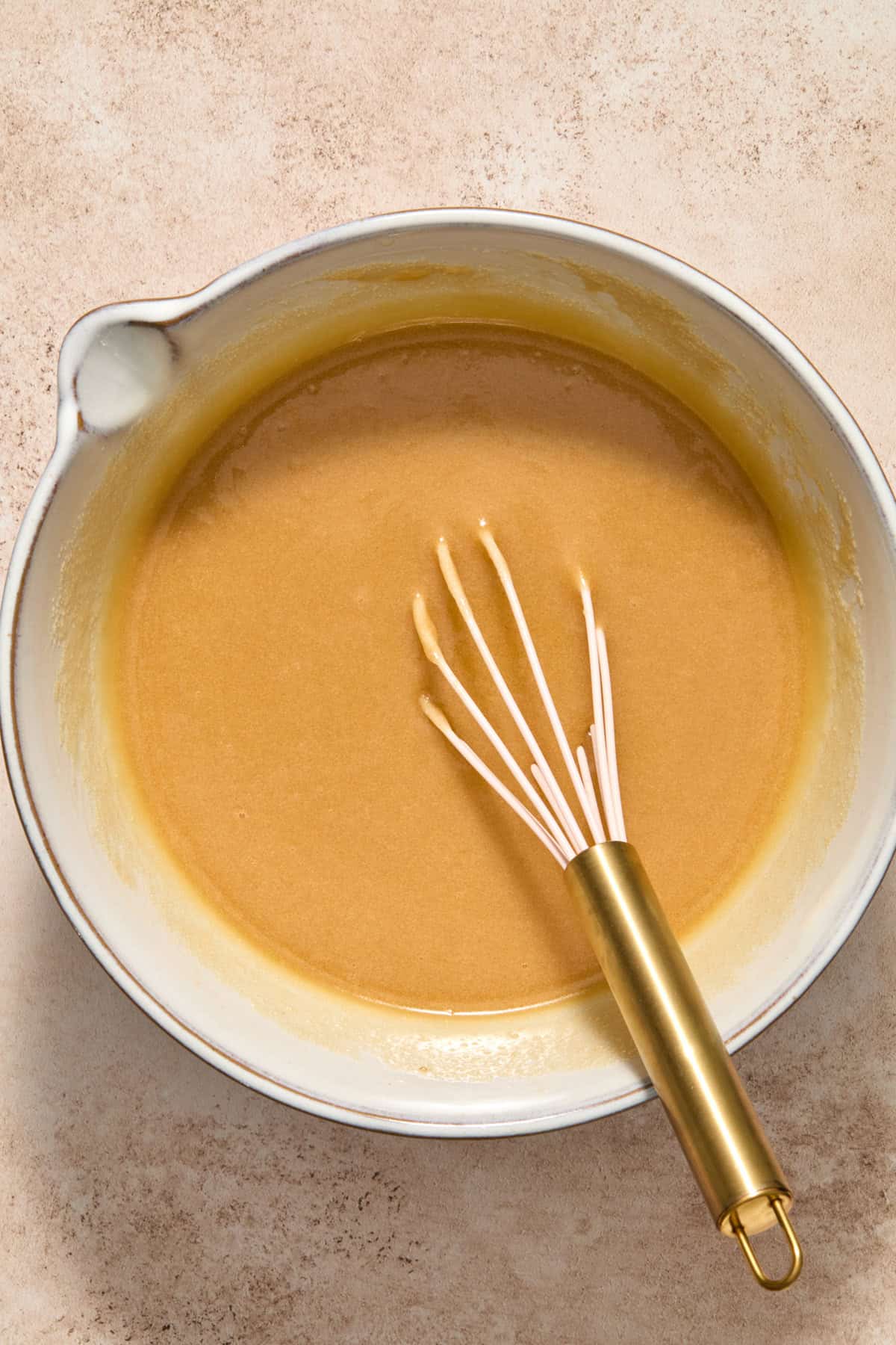Eggs and vanilla mixed into bowl with butter and sugars.