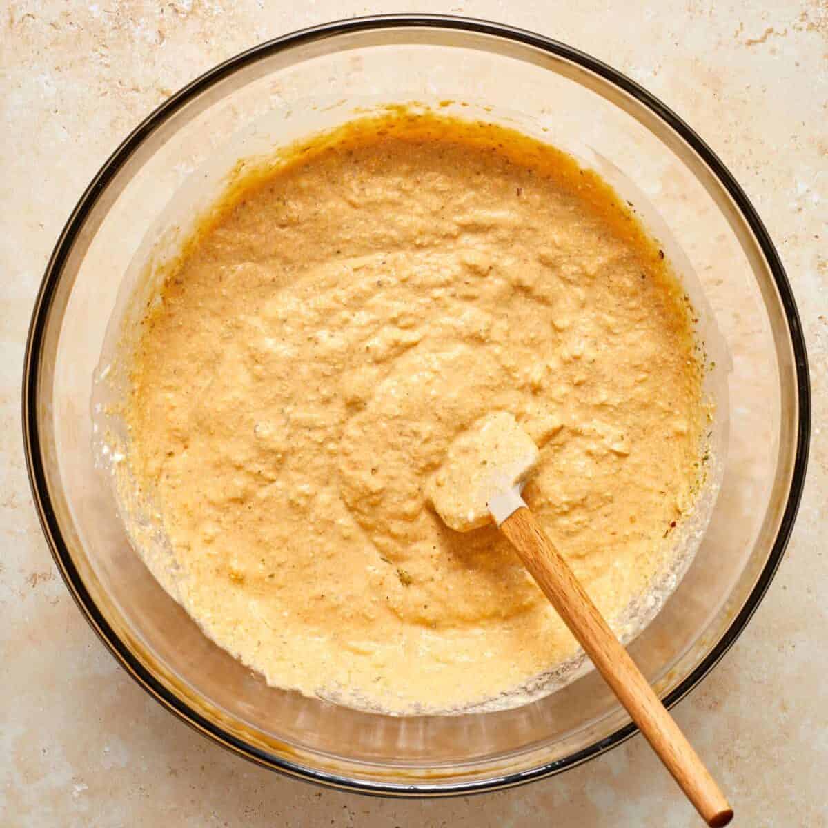 Pumpkin ricotta mixture in glass mixing bowl with spatula.
