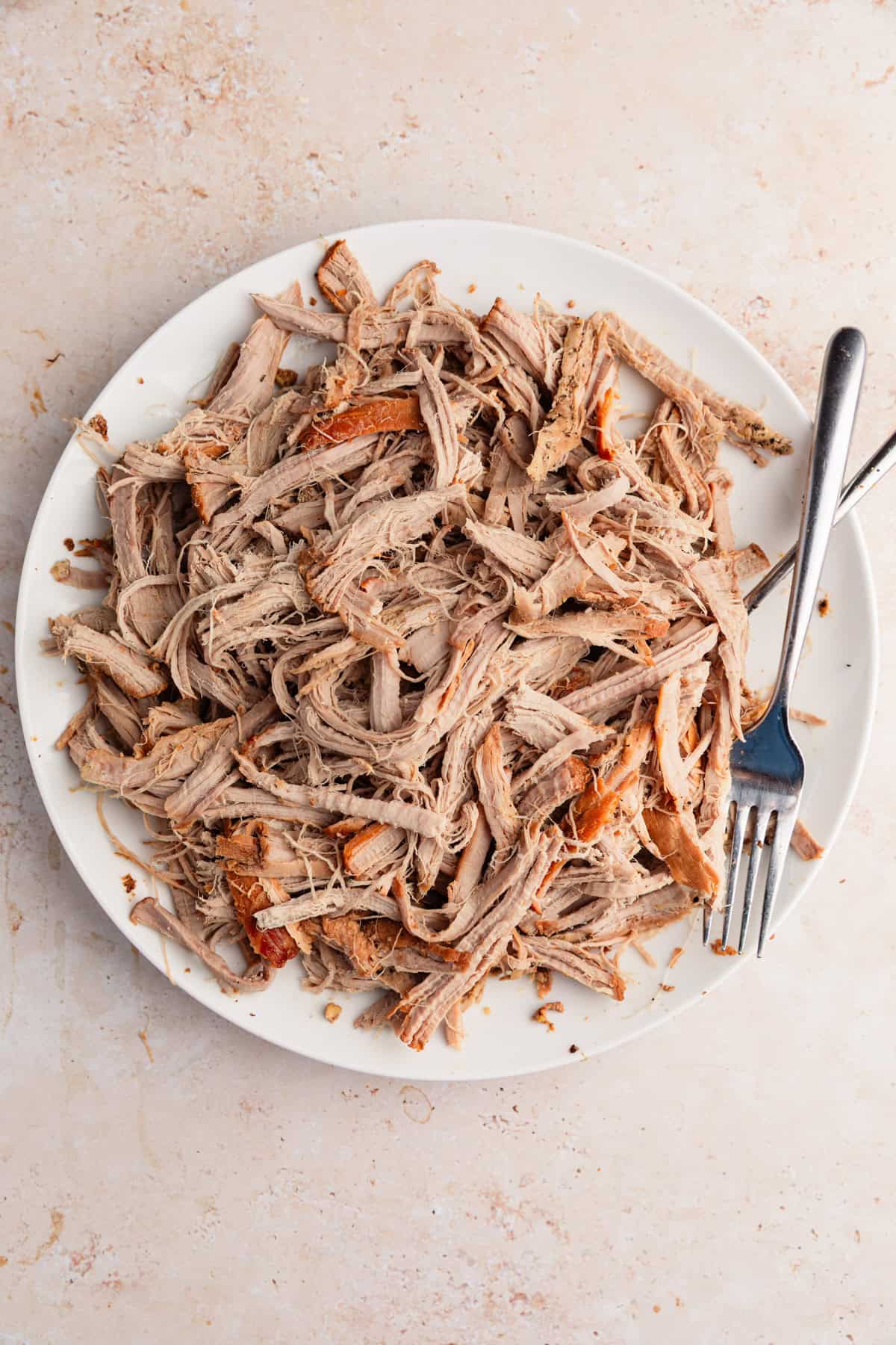 Pulled pork tenderloin on plate with forks.