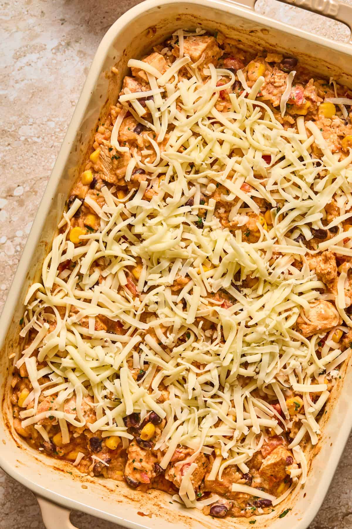 Shredded pepper jack cheese on chicken and rice bake before melted.
