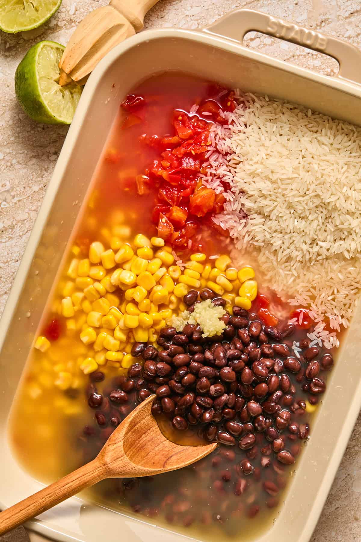 Baking pan with beans, corn, broth, lime juice and rice.
