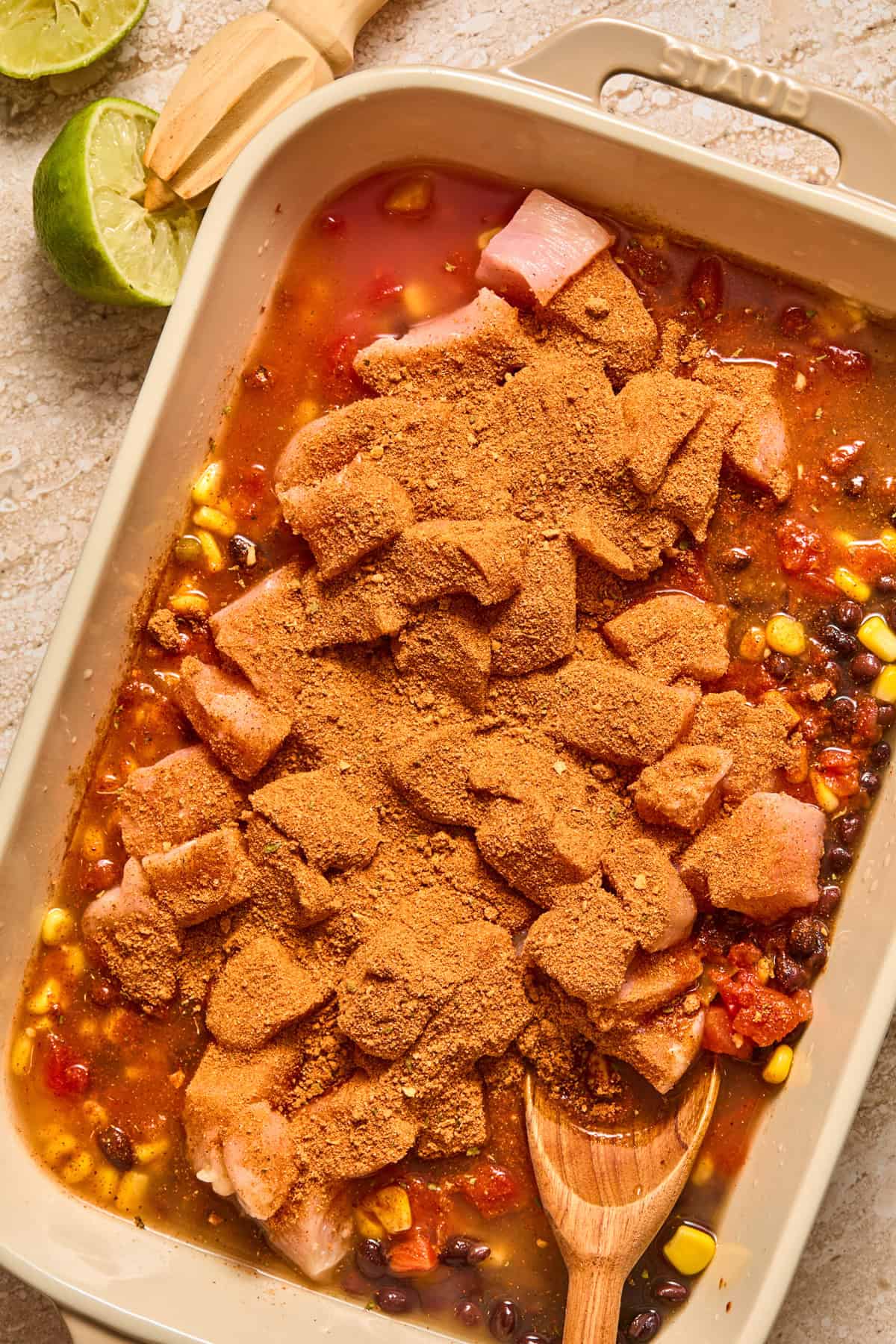 Chicken breast cubed in baking dish with taco seasoning over top.