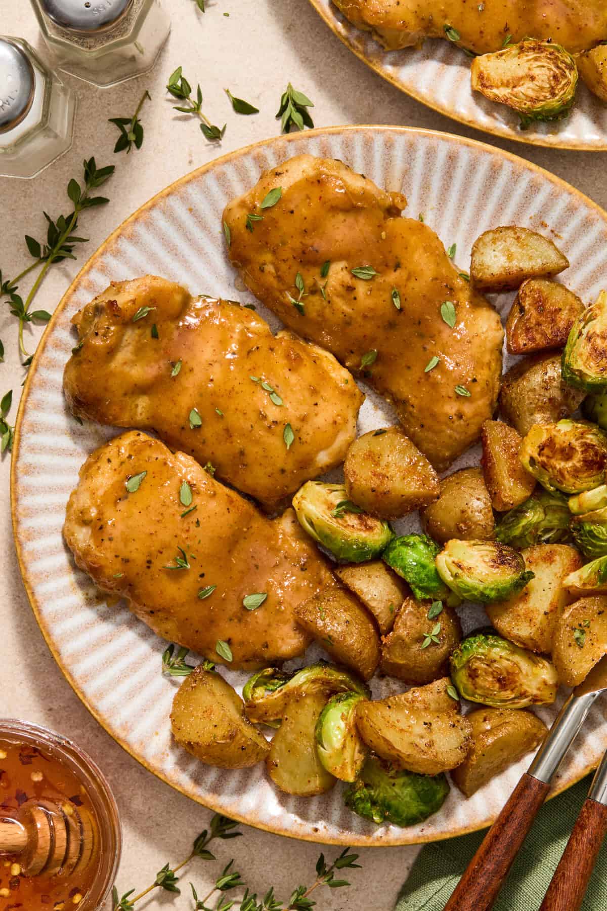 Honey mustard chicken, roasted potatoes and Brussels sprouts on plate with fork and knife.