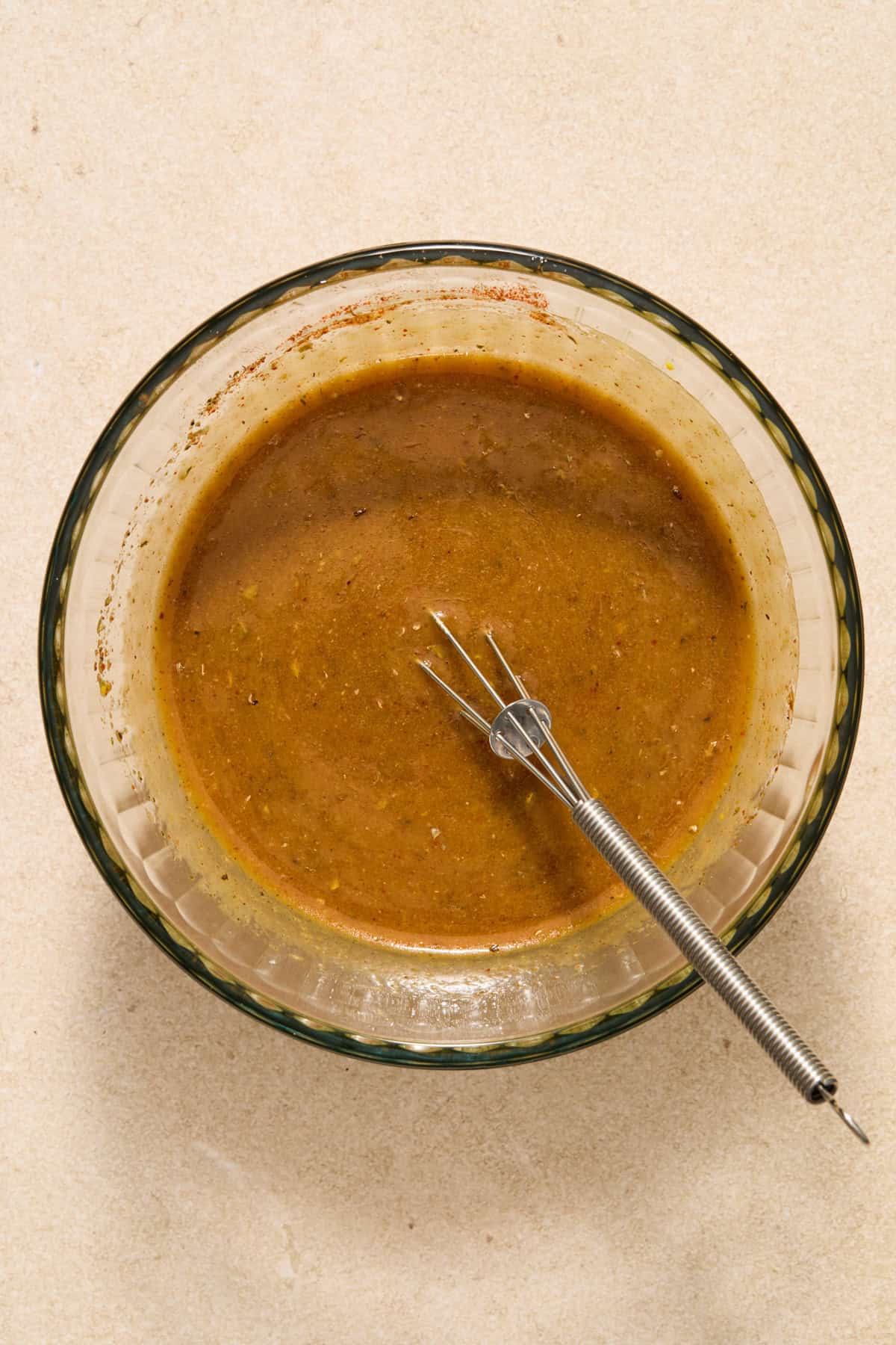Honey mustard marinade mixture in bowl with whisk.