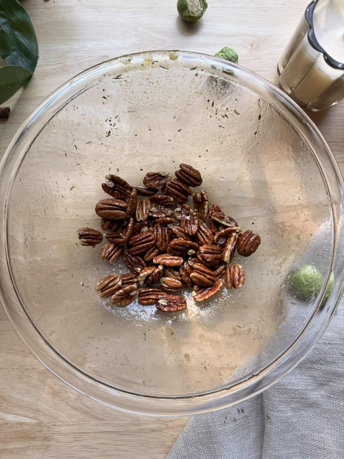 Pecans in maple dijon mixture in bowl.