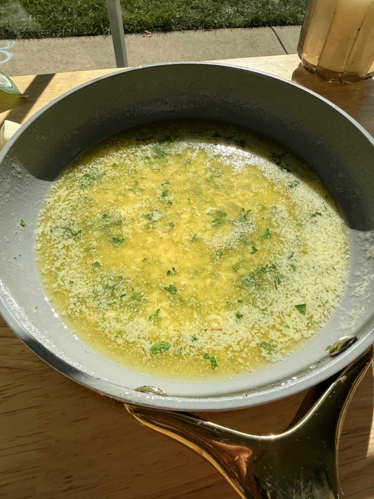 Garlic butter with herbs in skillet.