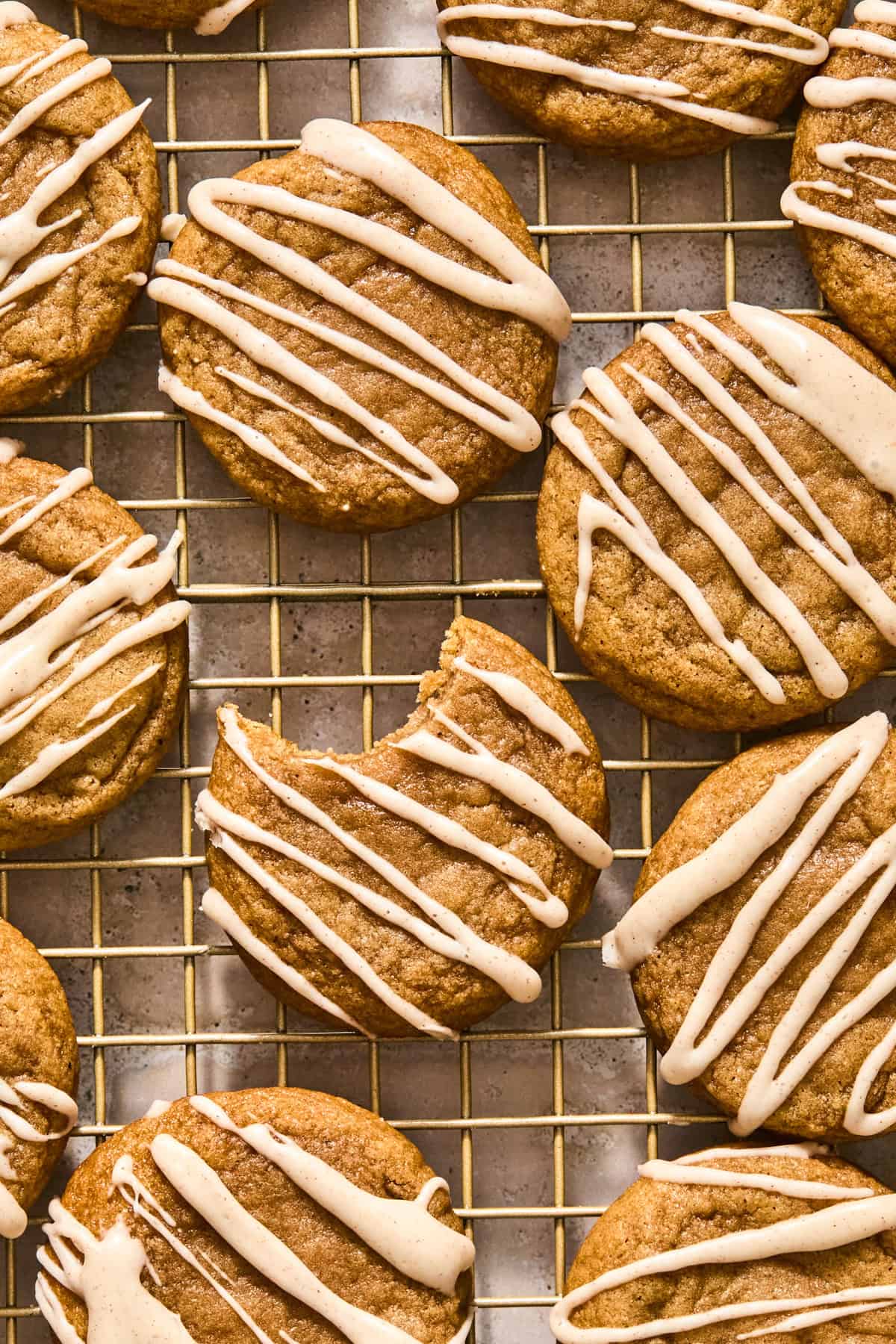 Icing drizzled cookies on cooling rack with bite taken out of one cookie.