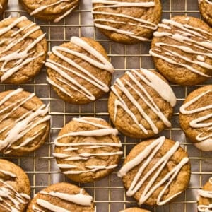 Maple and dark brown sugar cookies with icing drizzle on wire rack.