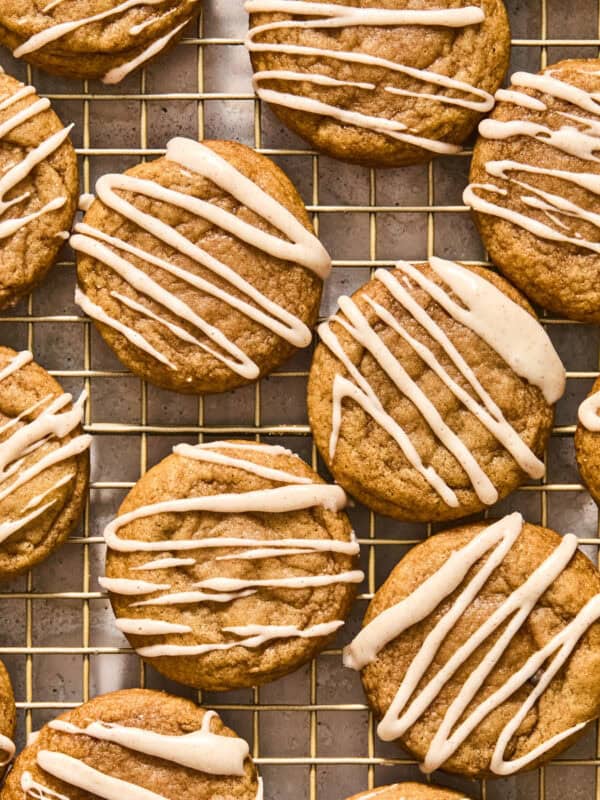 Maple and dark brown sugar cookies with icing drizzle on wire rack.