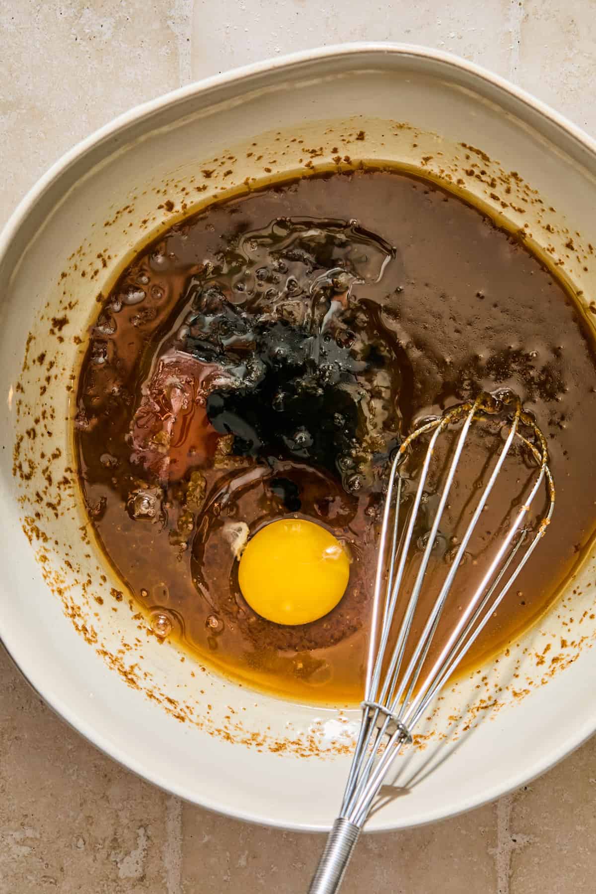 Egg, maple vanilla and other ingredients in bowl with whisk.