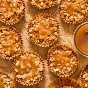Muffin cups with pumpkin crisp desserts topped with caramel sauce.