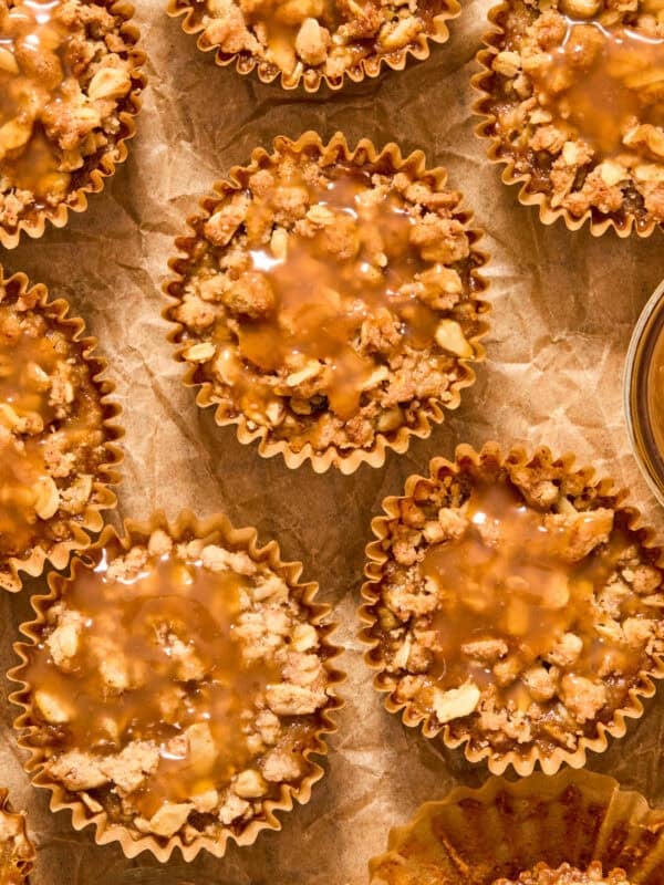 Muffin cups with pumpkin crisp desserts topped with caramel sauce.