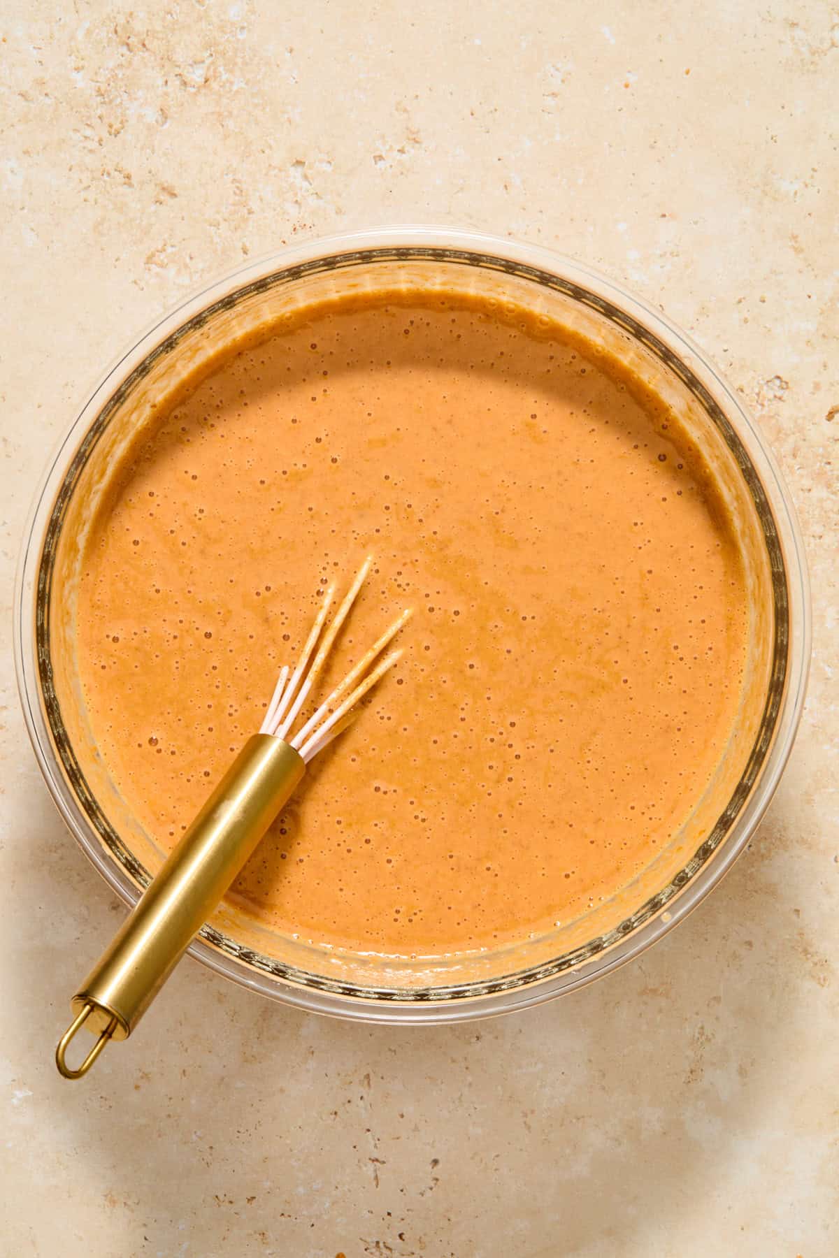 Pumpkin pie filling mixture in bowl with whisk.