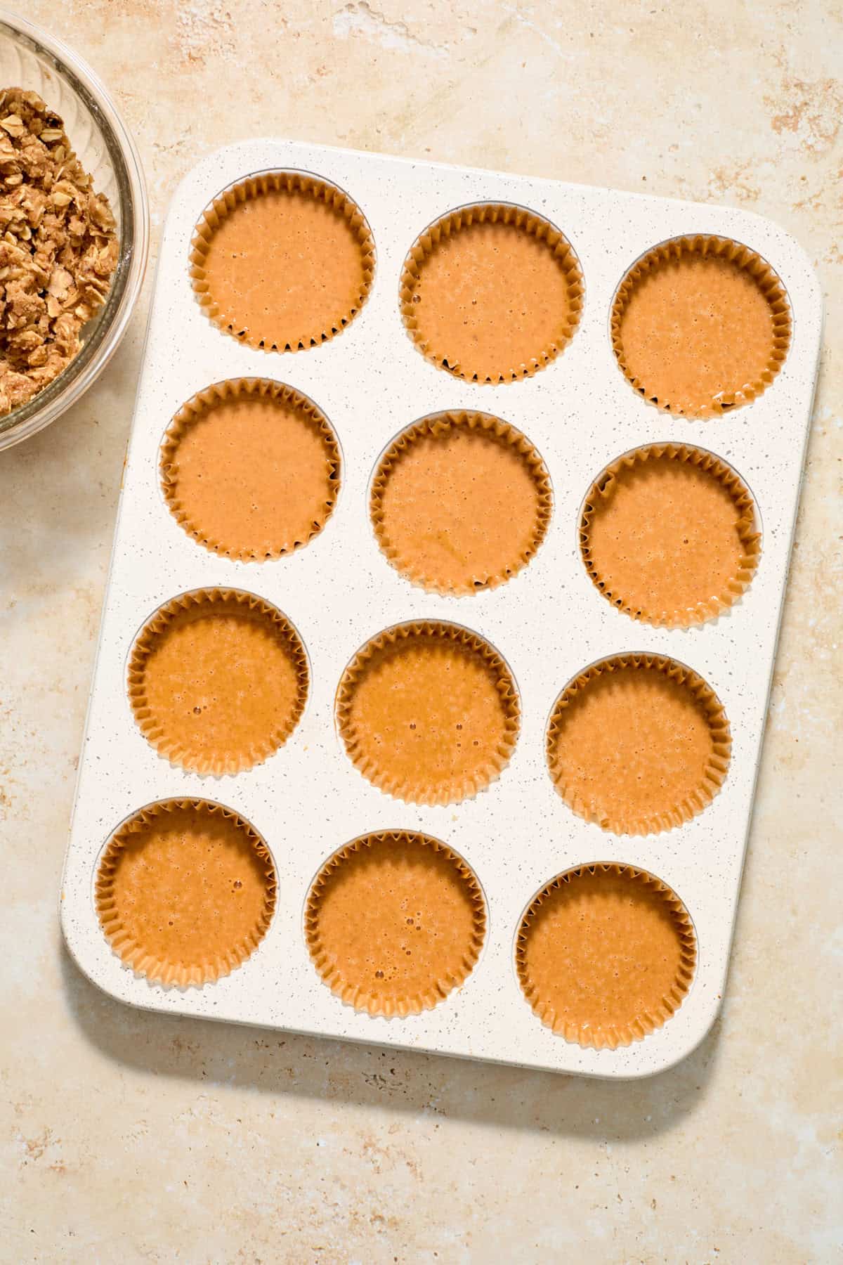 Pumpkin filling in muffin tin lined with cupcake liners.