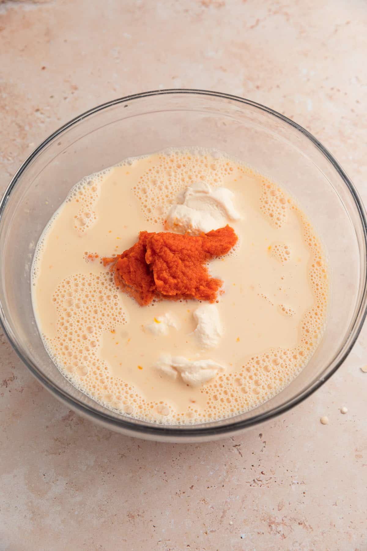 Wet ingredients with pumpkin and ricotta added to mixture in bowl.