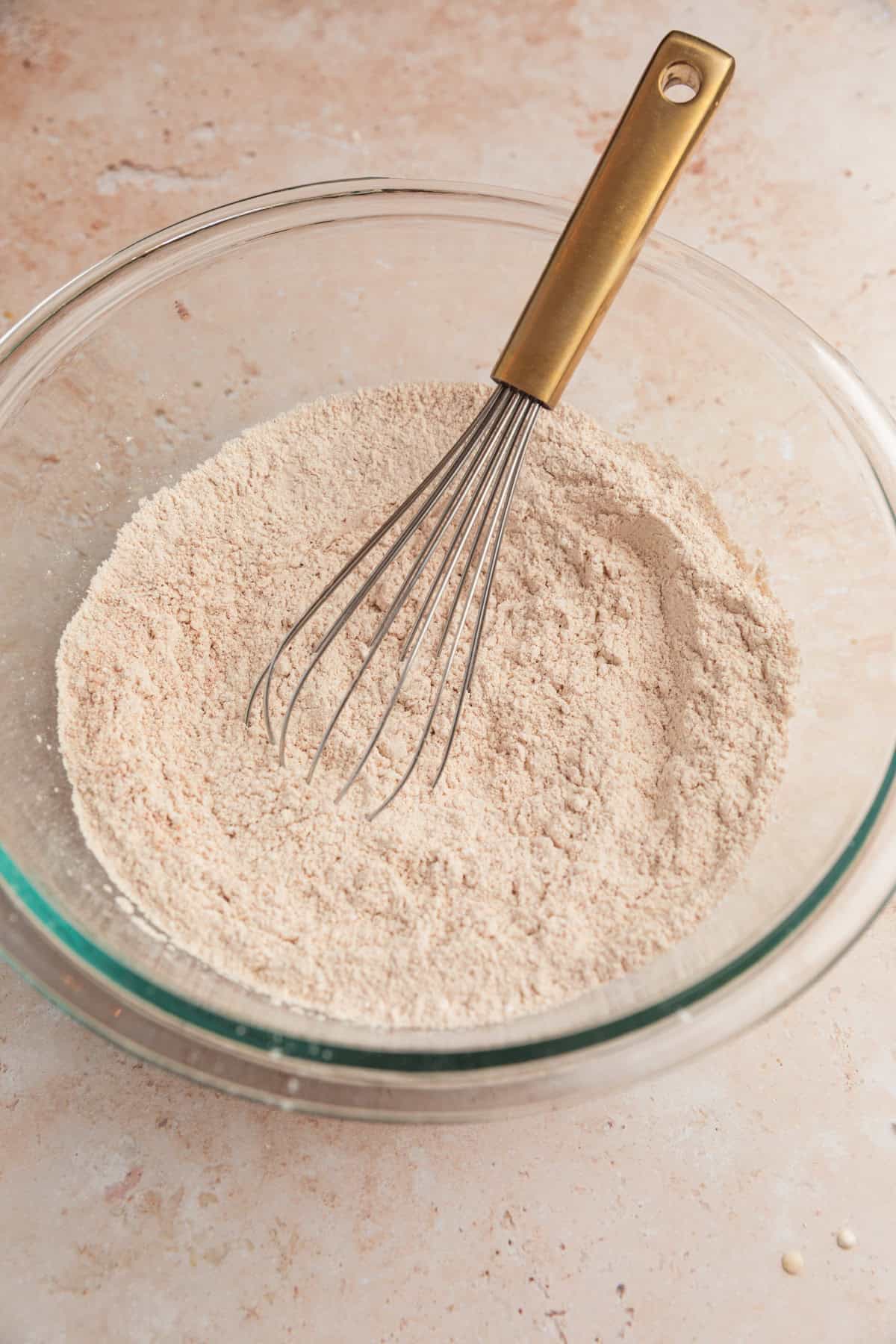 Dry ingredients with whisk in glass bowl.