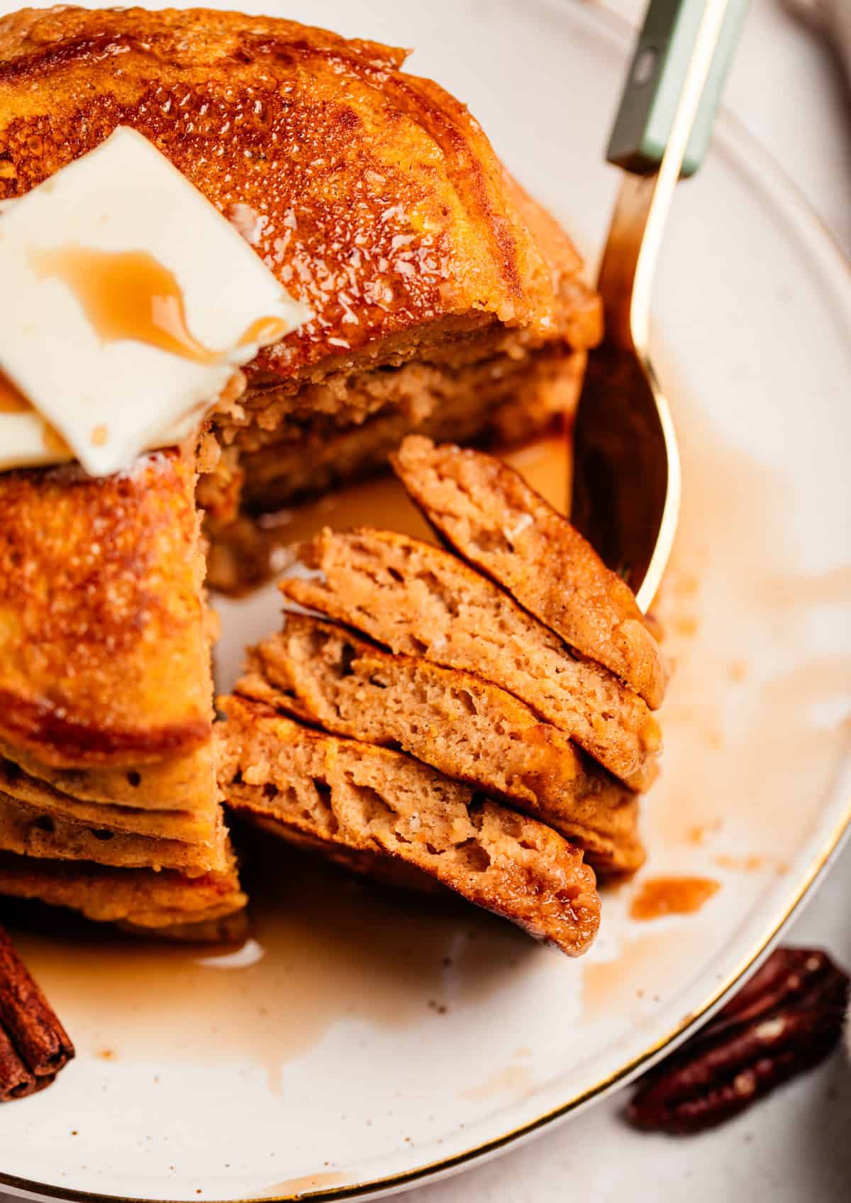 Fork with pieces of pancake on it propped on plate.