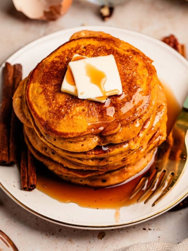 Pumpkin ricotta pancakes stack on plate with butter and syrup.
