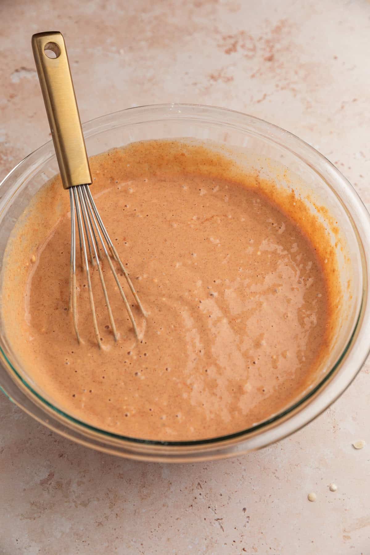 Prepared pumpkin ricotta pancake batter in bowl with whisk.