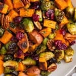 Roasted brussels sprouts and sweet potatoes on plate with pecans and cranberries.