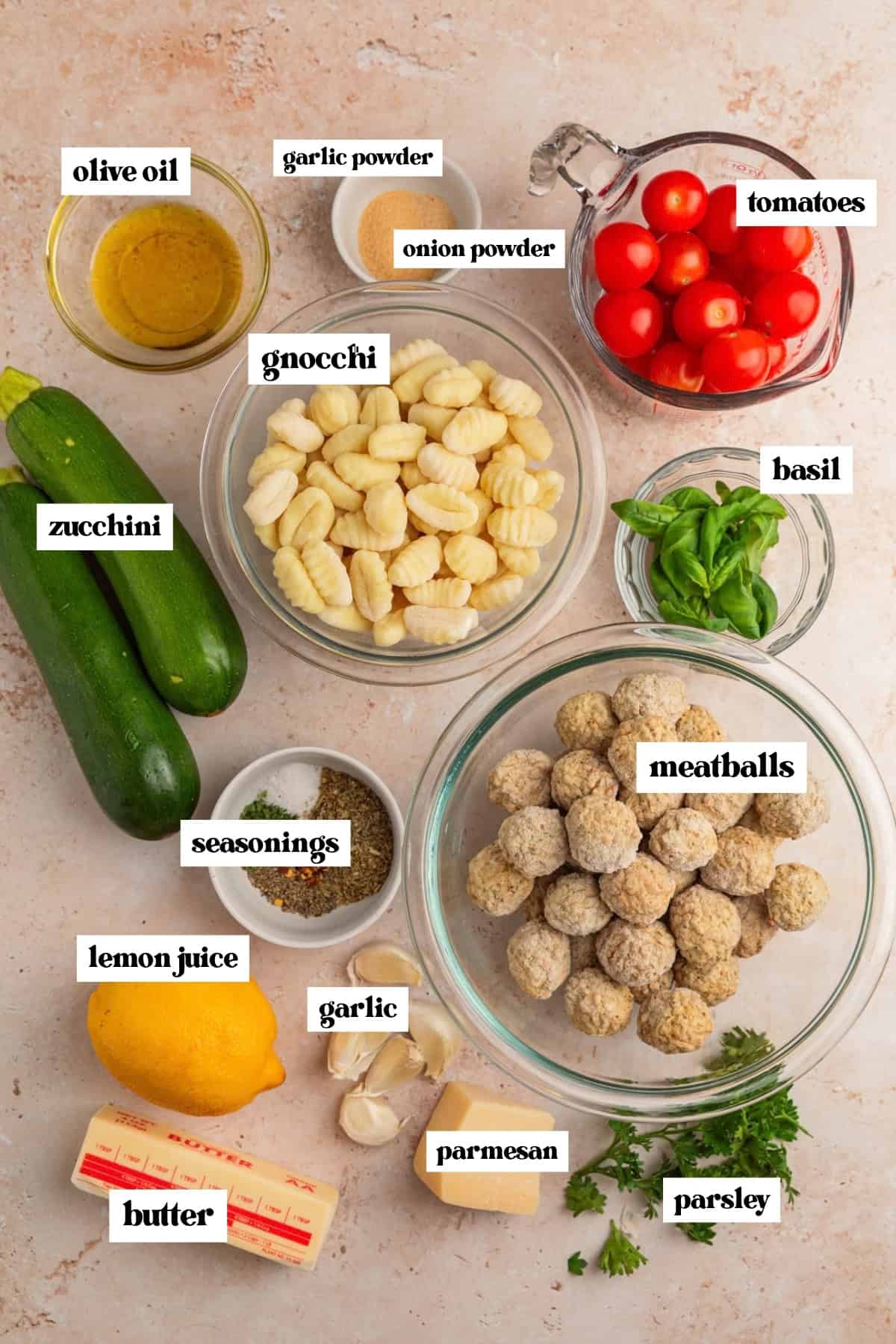 Zucchini, tomatoes, olive oil, potato gnocchi and other ingredients labeled on surface.